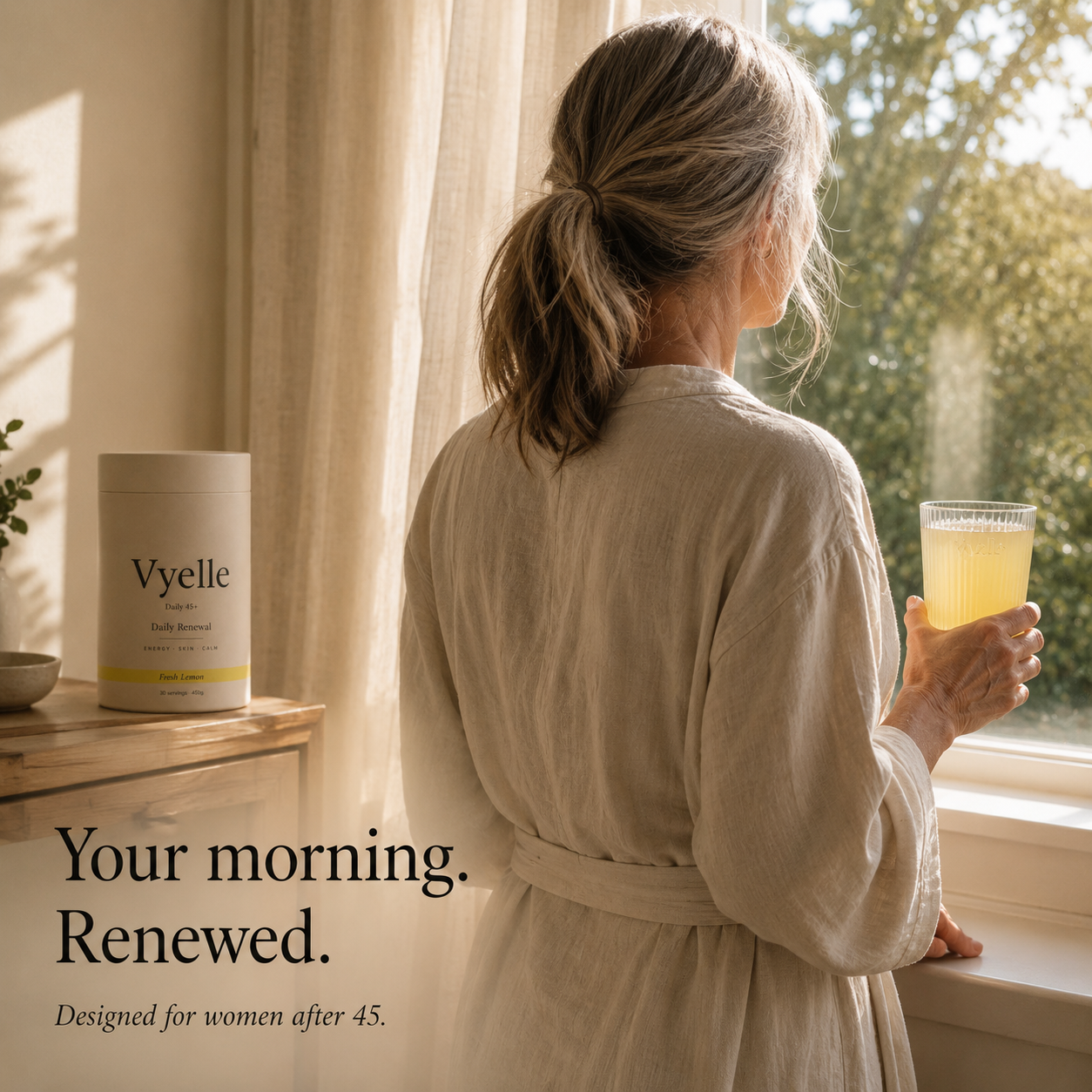 Woman over 45 standing at a sunlit morning window holding a ribbed Vyelle glass with pale lemon Fresh Lemon drink — the daily renewal ritual designed for women after 45.