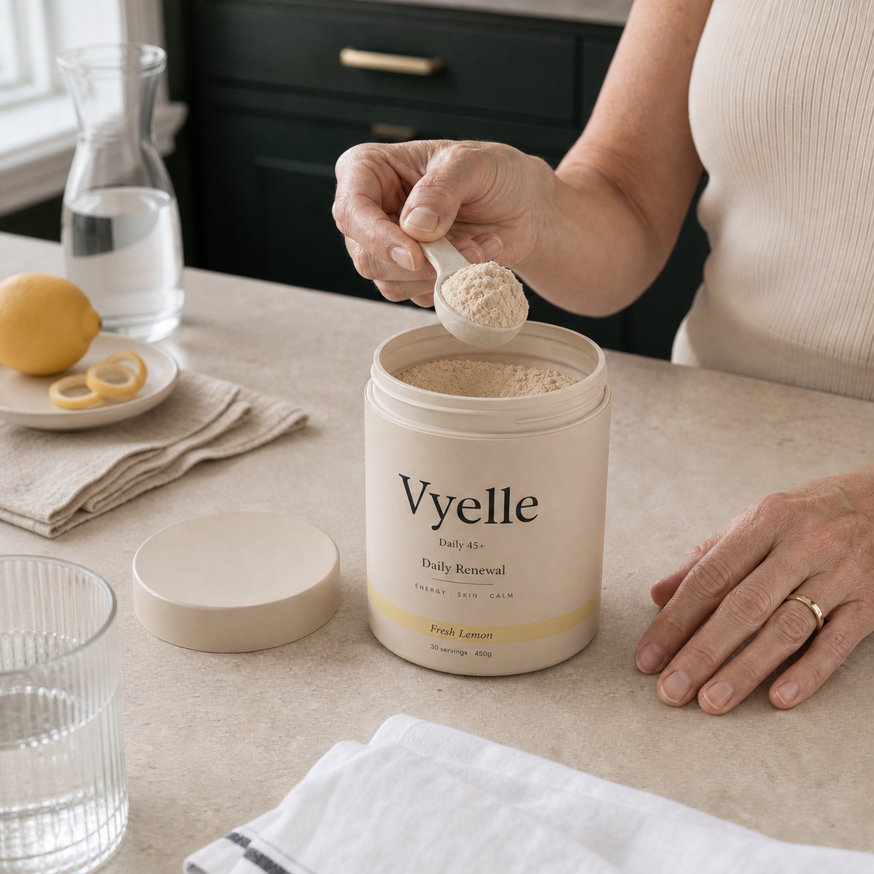 Hands scooping Vyelle powder from the open tub in a sunlit kitchen.